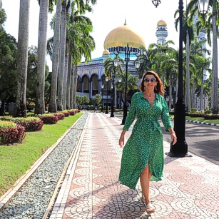 Elegant traveler woman walking in Brunei with a fancy green dress