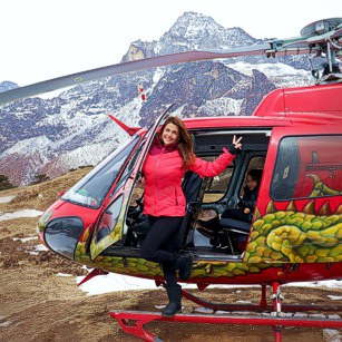 A woman outside of her rental helicopter makes a luxury travel to the slopes of Mount Everest