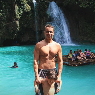 Father and son in swimsuits standing in Kawasan Falls in Philippines during a travel